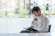 © amnaj - Portrait of young asian businessman sitting and thinking and analyzing documents at his desk in the office.
