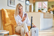 © Kalim - Businesswoman with luggage in modern hotel lobby using smartphone