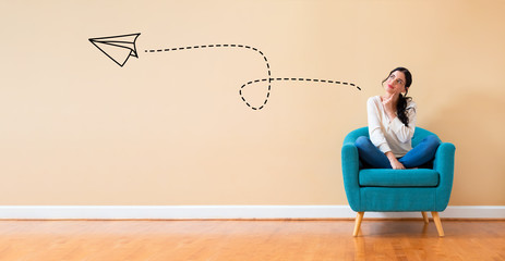 Poster - Paper airplane with woman in a thoughtful pose in a chair