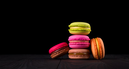 Heap of french colorful macaroons on wooden table isolated on black