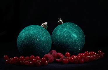 christmas balls and red fruits on black background