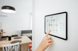 Controlling home with a digital touch screen panel installed on the wall. Close-up on a screen with mobile application for managing smart devices