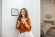 © rh2010 - Young woman controlling temperature in the living room with smart phone and digital touch screen panel. Concept of heating control in a smart home
