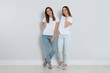 Young women in stylish jeans near light wall