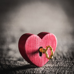 Wall Mural - small rustic red heart with shiny golden key on wooden table - valentine's day concept