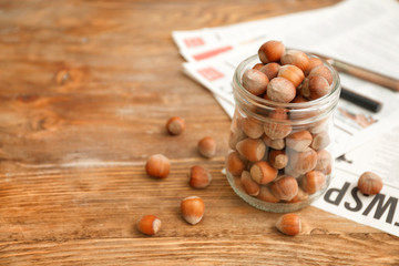 Wall Mural - Jar with tasty hazelnuts on wooden background