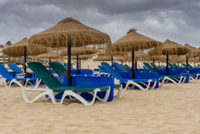 Rows Of Straw Parasols And Sunloungers On The Beach At Manta Rota, Algarve, Portugal.
