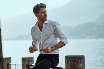 Stylish man in white classic shirt, looking at the mountains view