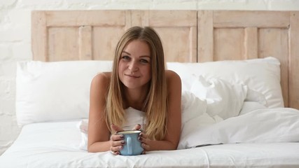 Wall Mural - Funny blonde with a cup of coffee in bed