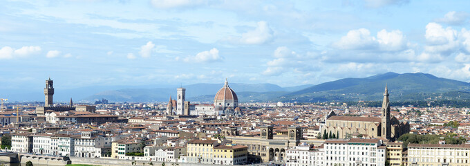 Panoramic view over Florence on a cloudy October day with cathedral, palazzo vecchio, giotto's bell tower, and other landmarks, with Tuscan hills in the back, as seen from Piazzale Michelangelo