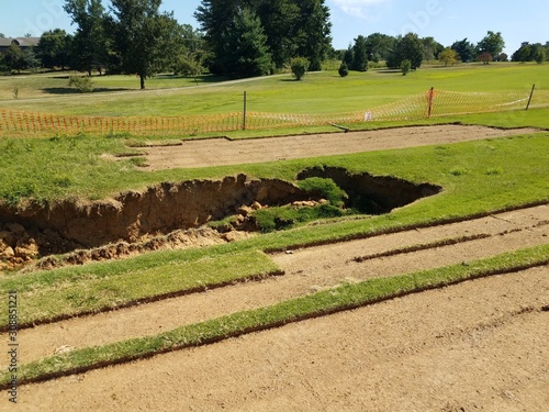 Fotografía sinkhole or erosion in grass and dirt on golf course