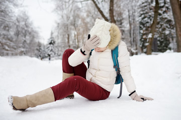 Shot of person during falling in snowy winter park. Woman slip on the icy path, fell and lies.