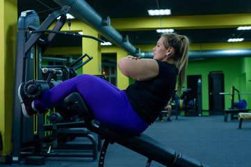 Wall Mural - Fat woman trying to lose weight and doing bench press exercises on the press bench in the gym. Overweight blonde is engaged in fitness.