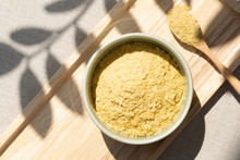 Top View & Closeup, Yellow Flakes Of Nutritional Yeast In Ceramic Bowl And Wooden Spoon, Excellent Source Of Vitamins, Minerals, And High-quality Protein For Plant-based Diet / Vegan Food.