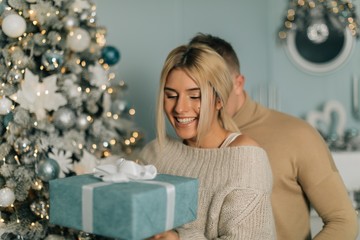 picture of romantic couple in a sweaters with gift box. Boy give a Christmas gift to her girlfriend. Happy young couple background. Magic card.