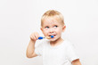 © yana136 - little cute caucasian blond blue-eyed boy in a white t-shirt brushes his teeth on a white background with copy space