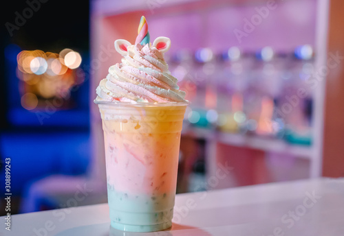 A cup of unicorn smoothie, rainbow ice cream mixed with blueberry syrup topped with whipping cream, white chocolate and marshmallow.(Unicorn Frappe)