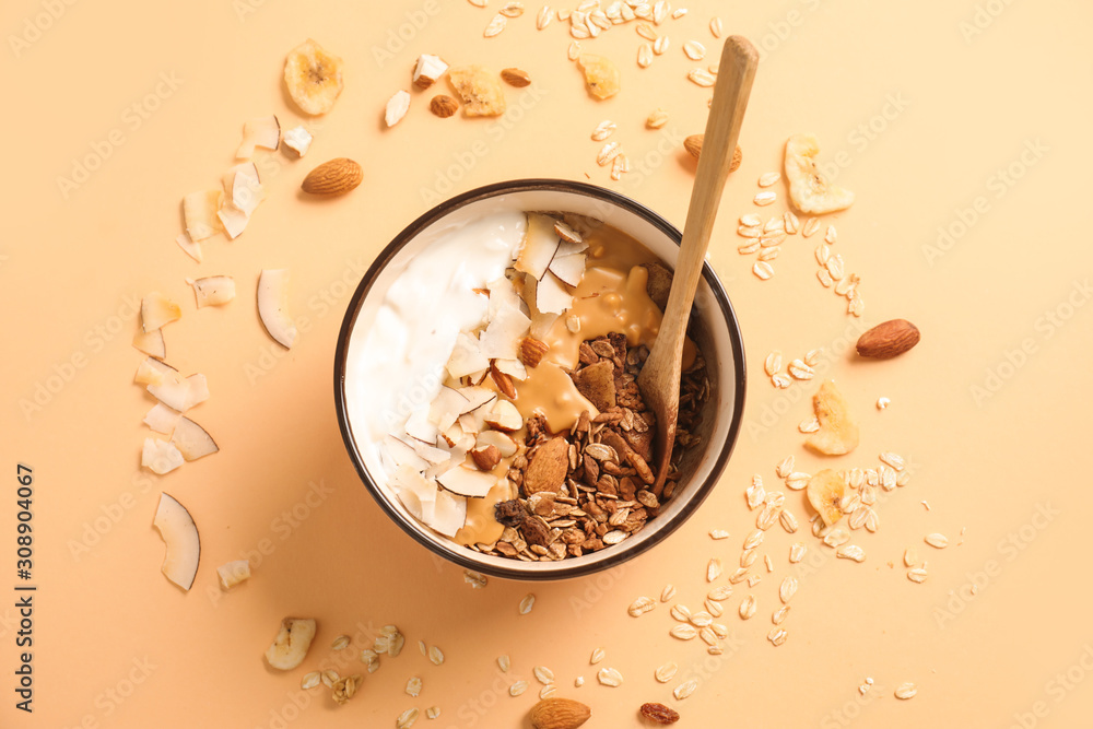 Tasty granola with yogurt in bowl on color background