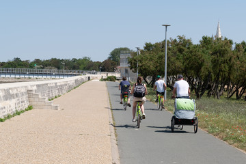 alley ride bikeway bike family with trailer in La Rochelle France near Atlantic ocean