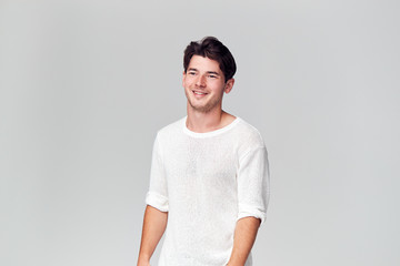 Studio Portrait Of Young Man Wearing White T Shirt Smiling Off Camera