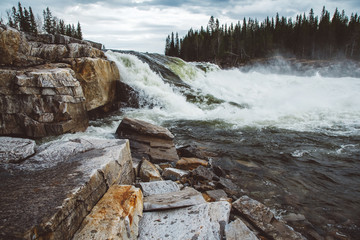 Wall Mural - waves and splashes of mountain river on background of forest, rocks and dramatic sky. forest river w