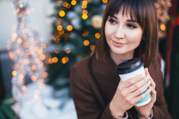 Wall Mural - Woman drinking coffee on Christmas city street.