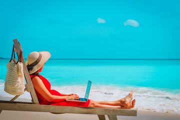 Wall Mural - remote work concept -young woman with laptop on beach