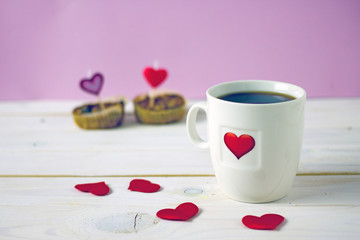 Canvas Print - Valentine's Day breakfast. White mug of tea with a heart pattern and and two homemade cupcakes with candle hearts on a pink background. Copy space