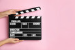 © New Africa - Woman holding clapperboard on pink background, closeup with space for text. Cinema production