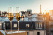 Celebration of New Year or Christmas concept. Two glasses with champagne and golden decorations on a balcony with a view on rooftops and Eiffel Tower. Romantic or celebration concept