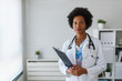 © lordn - Portrait of female African American doctor standing in her office at clinic