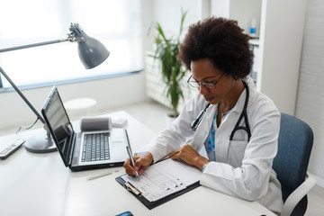 Wall Mural - Serious concentrated African American doctor working in her office at clinic