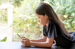 © maemanee - Young girl with long black hair laying down on terrace with mobile phone at home in countryside. Pre teen Asian student reading text or typing message on her smartphone.Technology and network concept.