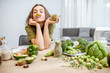 © rh2010 - Portrait of a young cheerful woman with lots of healthy green food on the table. Concept of vegetarianism and well-being