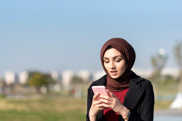 Wall Mural - muslim young woman typing message with her smartphone