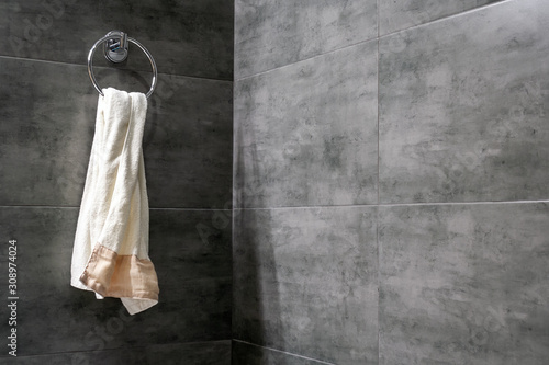 Fotomural A light terry towel hangs on a chromed ring holder on a gray concrete wall in th