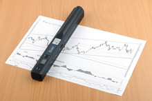 A Portable Handheld Black Scanner For Documents And Papers Located On The Document