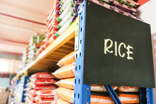Rice Signage With Stacks Of Rice On Shelf Of Supermarket