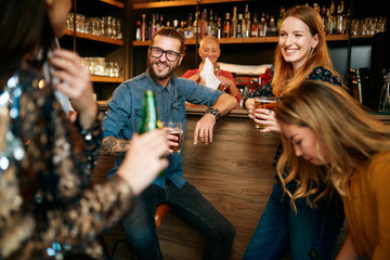 Poster - Group of friends drinking beer, chatting and talking to barman. Night out. Pub interior.