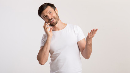 Poster - Man Talking On Cellphone Gesturing And Smiling On White Background