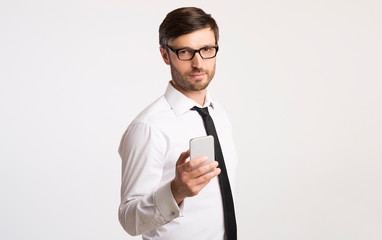 Poster - Business Guy Holding Phone Looking At Camera Standing In Studio