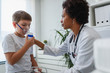 © lordn - Woman African American doctor general practitioner helping child to put nebulizer inhaler face mask. Asthma treatment for children.