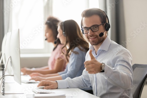 Fotografía Smiling male employee in headset show thumb up