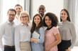 © fizkes - Smiling multiethnic employees posing together for group picture