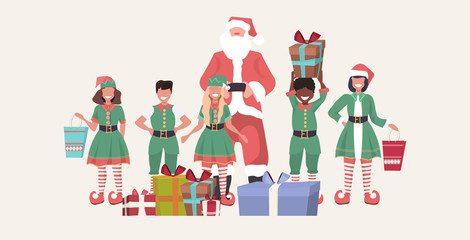 Wall Mural - santa claus with mix race elves standing together near gift boxes merry christmas happy new year holiday presents concept horizontal full length sketch vector illustration