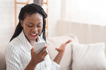 Angry african american girl screaming on cellphone, tired of annoying calls