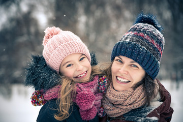 Little girl and her mother playing outdoors at winter day. Active winter holydays concept.