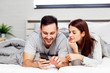 © pucko_ns - Couple in bed looking at mobile phone