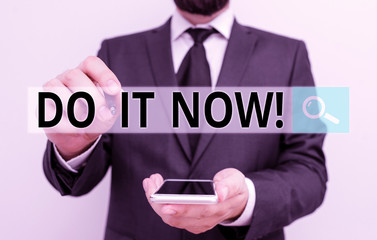 Wall Mural - Text sign showing Do It Now. Business photo showcasing not hesitate and start working or doing stuff right away Male human wear formal work suit hold smart hi tech smartphone use one hand