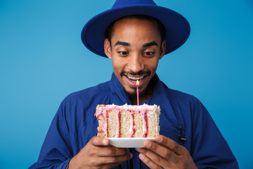 Wall Mural - Photo of delighted african american man holding cake with candle